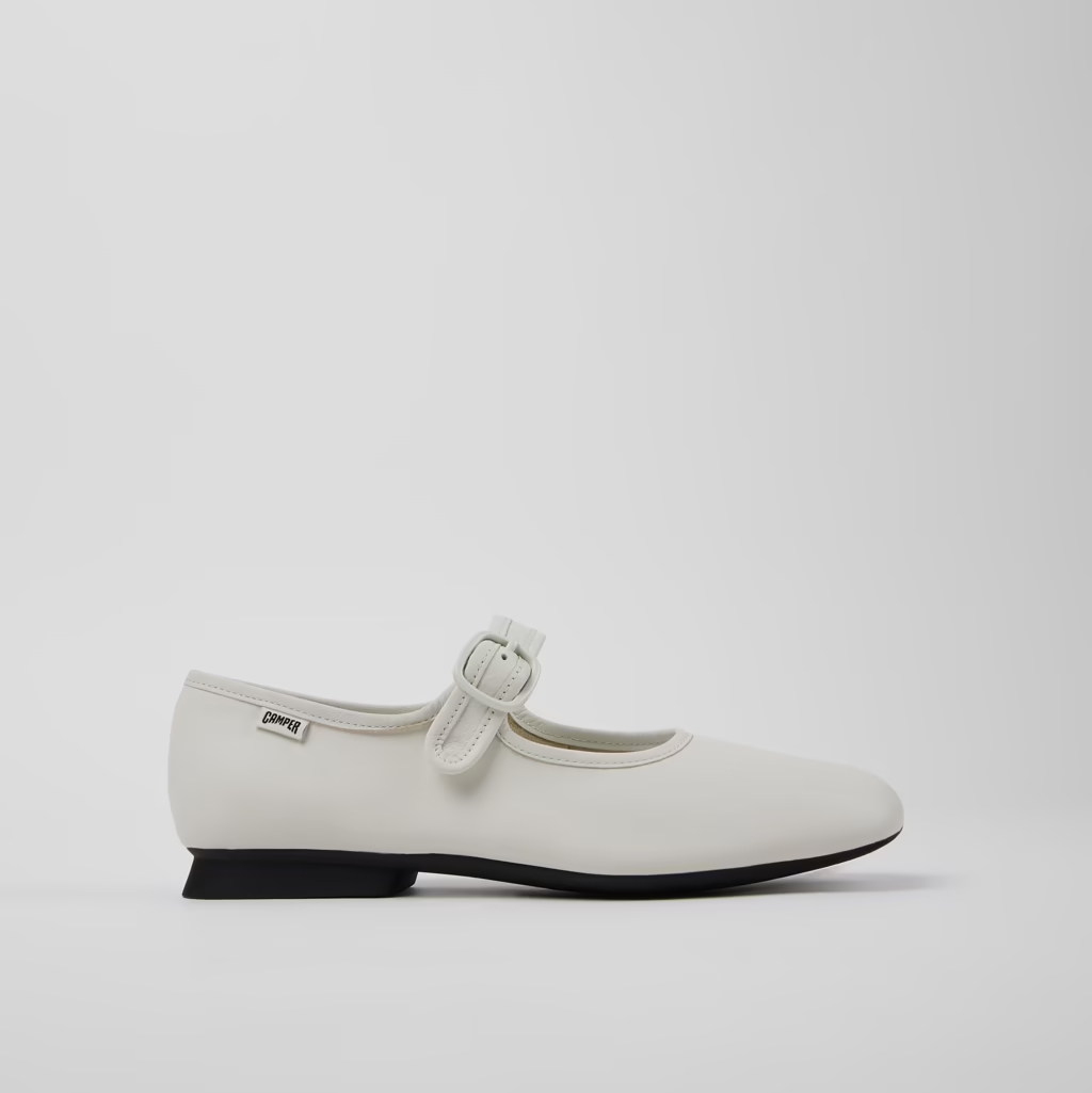 White flat shoe with a strap on a light gray background