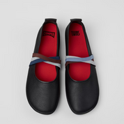 Black shoes with red insoles and blue straps on a light gray background