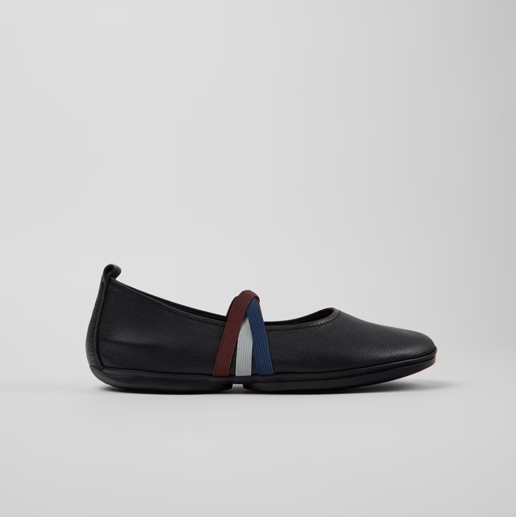 Black slip-on shoe with colorful accents on a light gray background