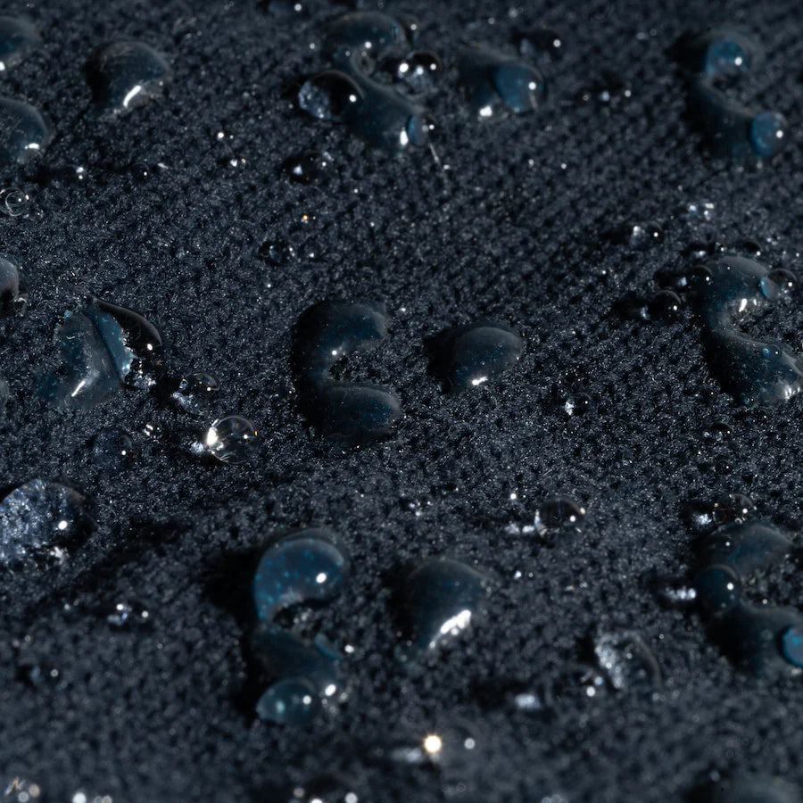 Close-up of dark sand with water droplets on a blue background