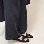 Person wearing black wide-leg pants and black shoes with white patterns on a beige background