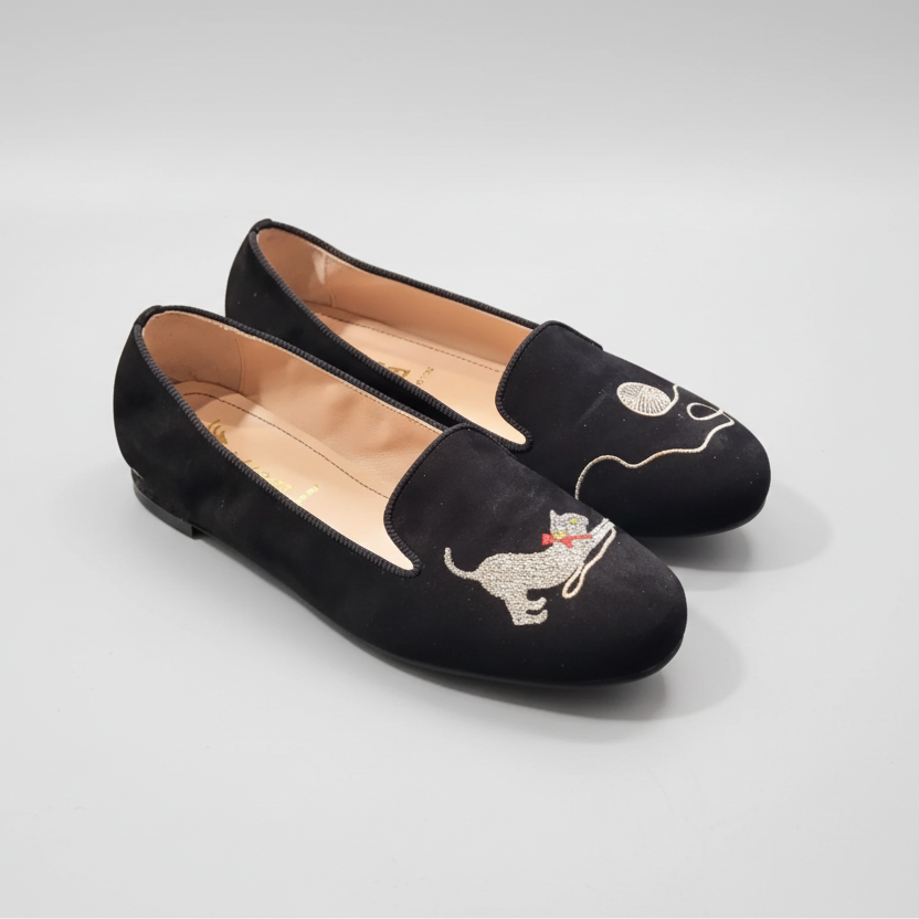 Black loafers with dog embroidery on a light gray surface