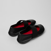 Black shoes with red lining on a light gray background