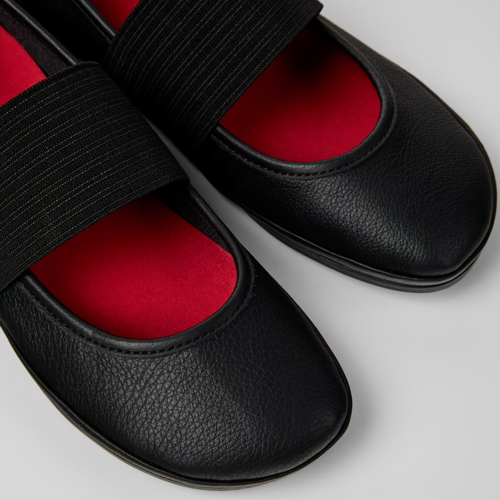 Black slippers with red soles on a light gray background