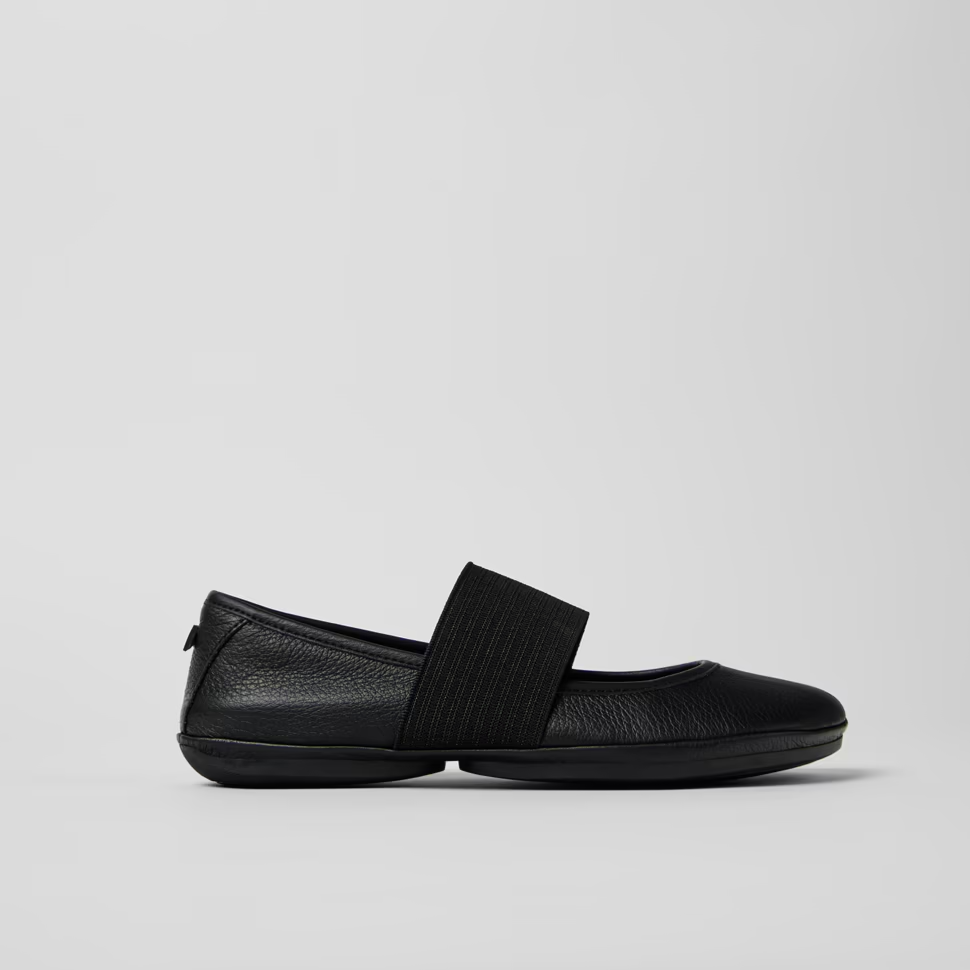 Black slip-on shoes with a strap on a light gray background
