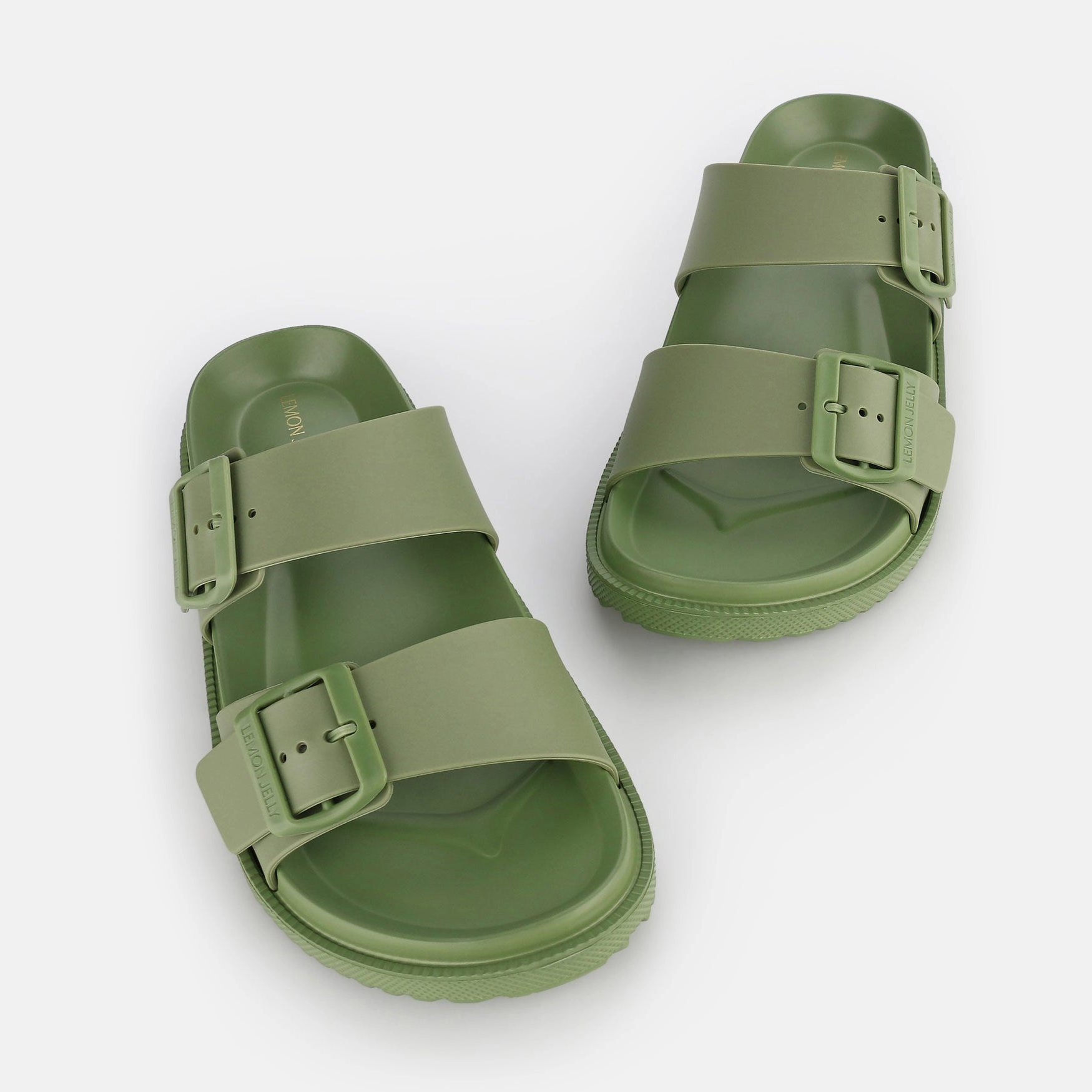 Pair of green sandals with buckles on a white background