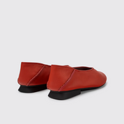 Pair of red shoes with black soles on a white background