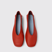 Pair of red shoes with gray insoles on a white background