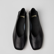 Pair of black shoes with 'Camper' branding on a light gray background