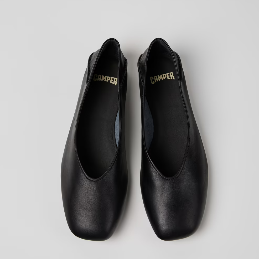 Pair of black shoes with 'Camper' branding on a light gray background
