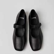 Pair of black shoes with buckles on a light gray background