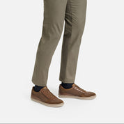 Brown sneakers worn with beige pants on a white background