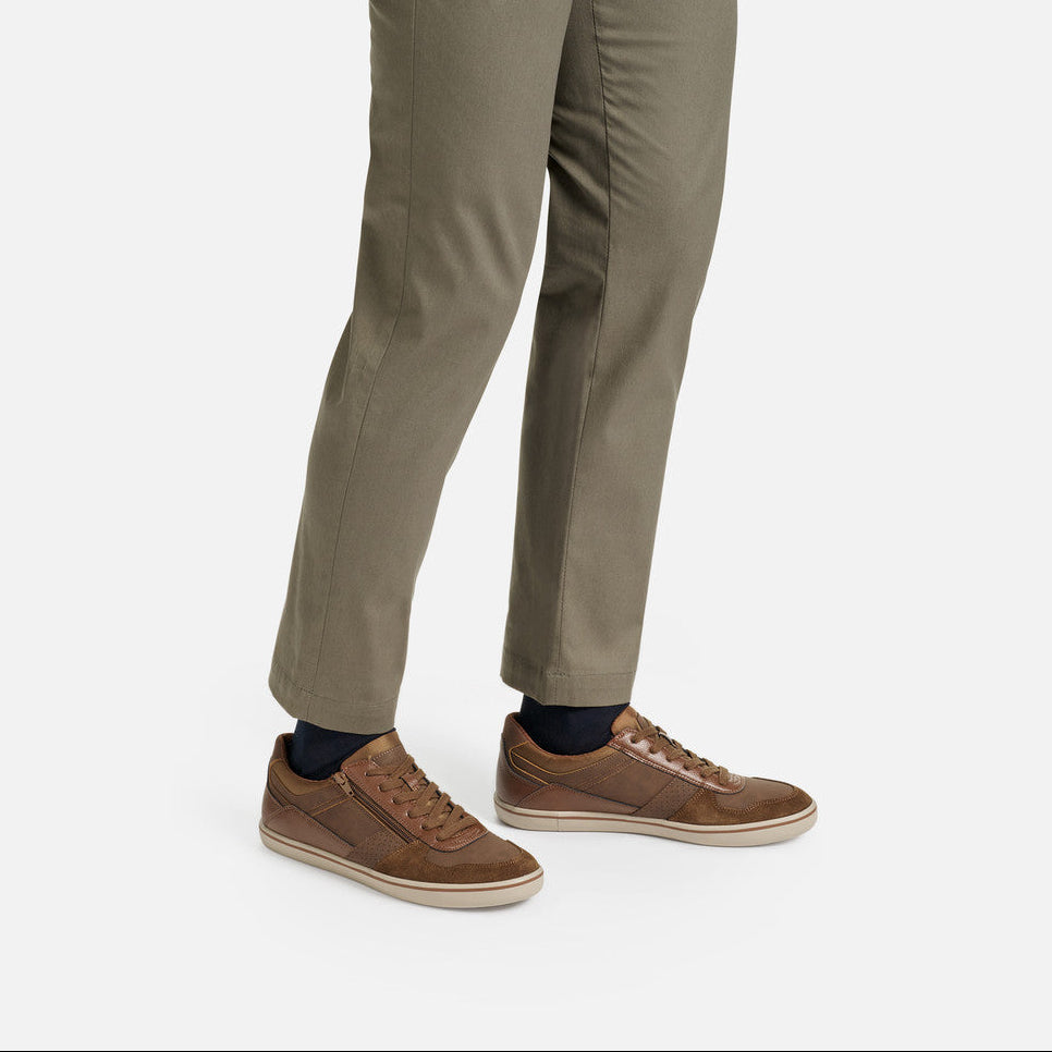 Brown sneakers worn with beige pants on a white background