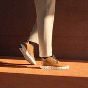 Person wearing brown shoes with white soles on a brown surface