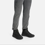 Person wearing black boots and gray jeans on a white background