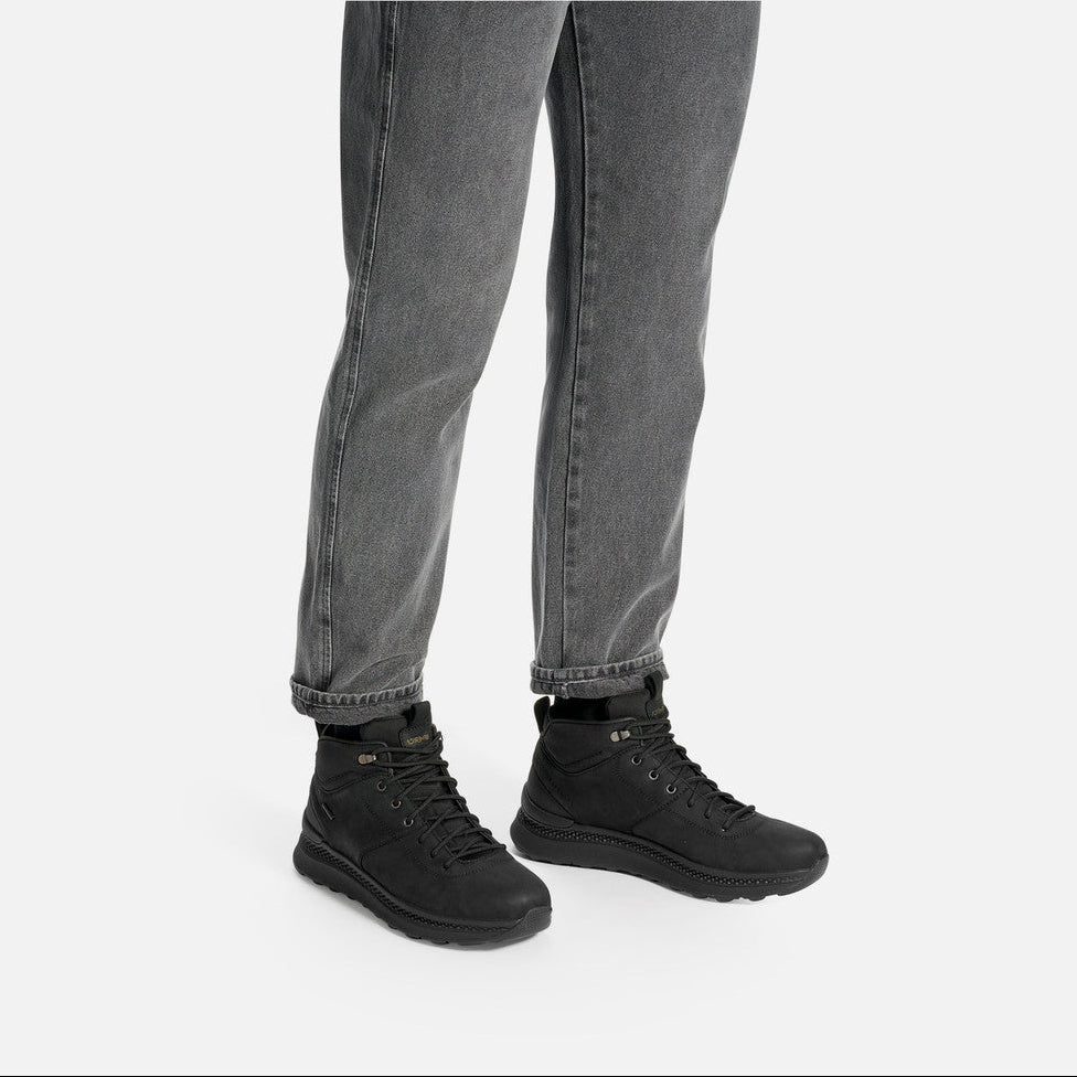 Person wearing black boots and gray jeans on a white background