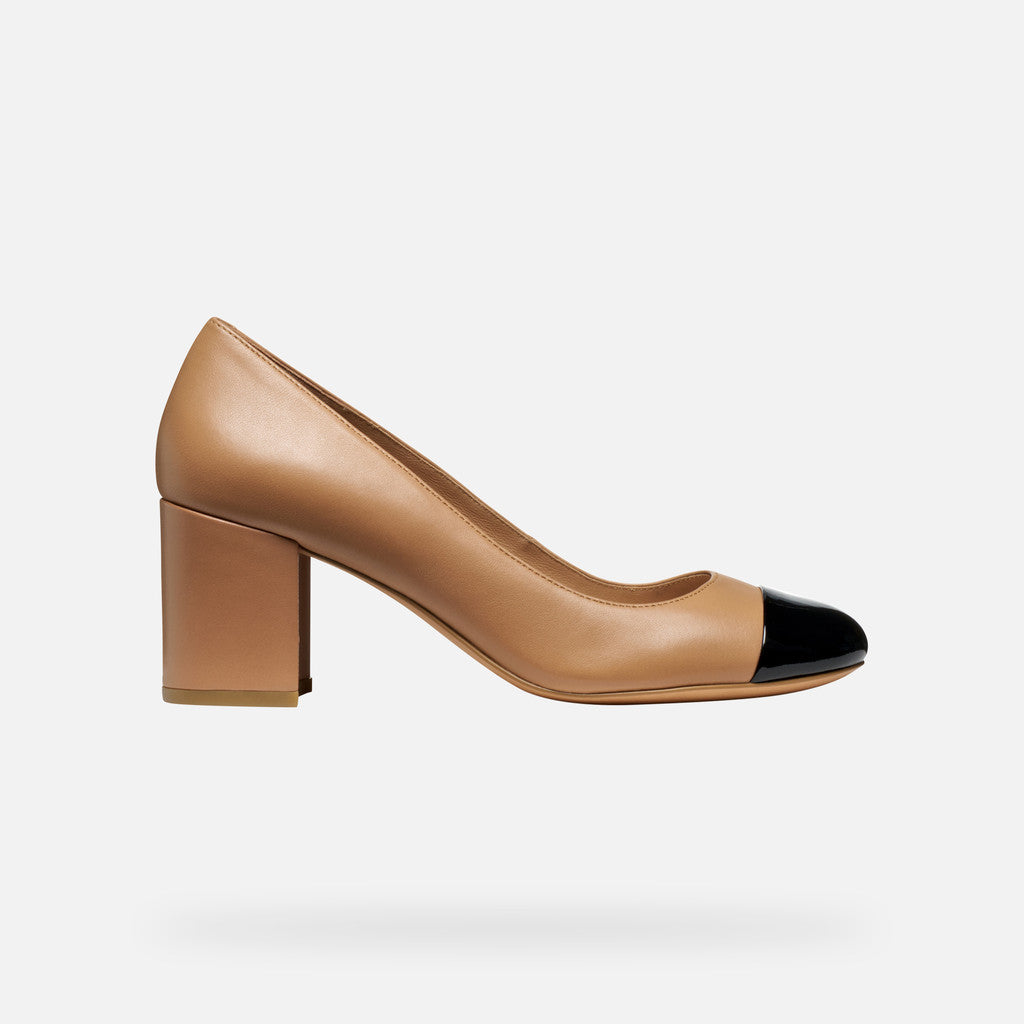 Tan high heel shoe with black cap toe on a white background