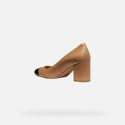 Tan high heel shoe with black toe cap on a white background