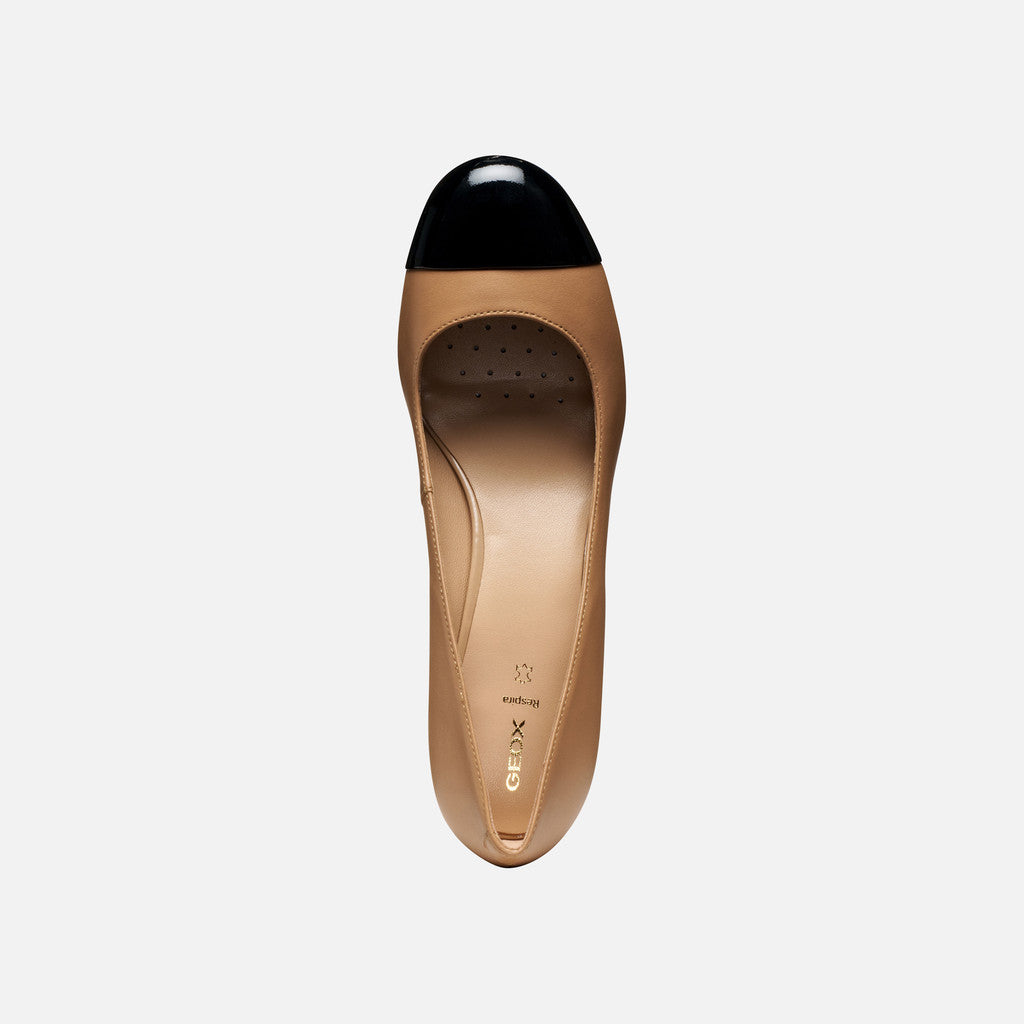 Tan shoe with black cap toe on a white background