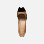 Tan shoe with black cap toe on a white background