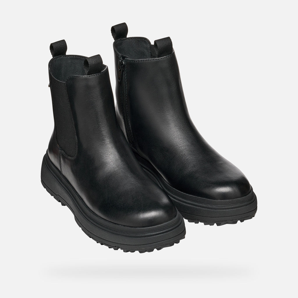 Pair of black leather boots on a light gray background