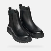 Pair of black leather boots on a light gray background