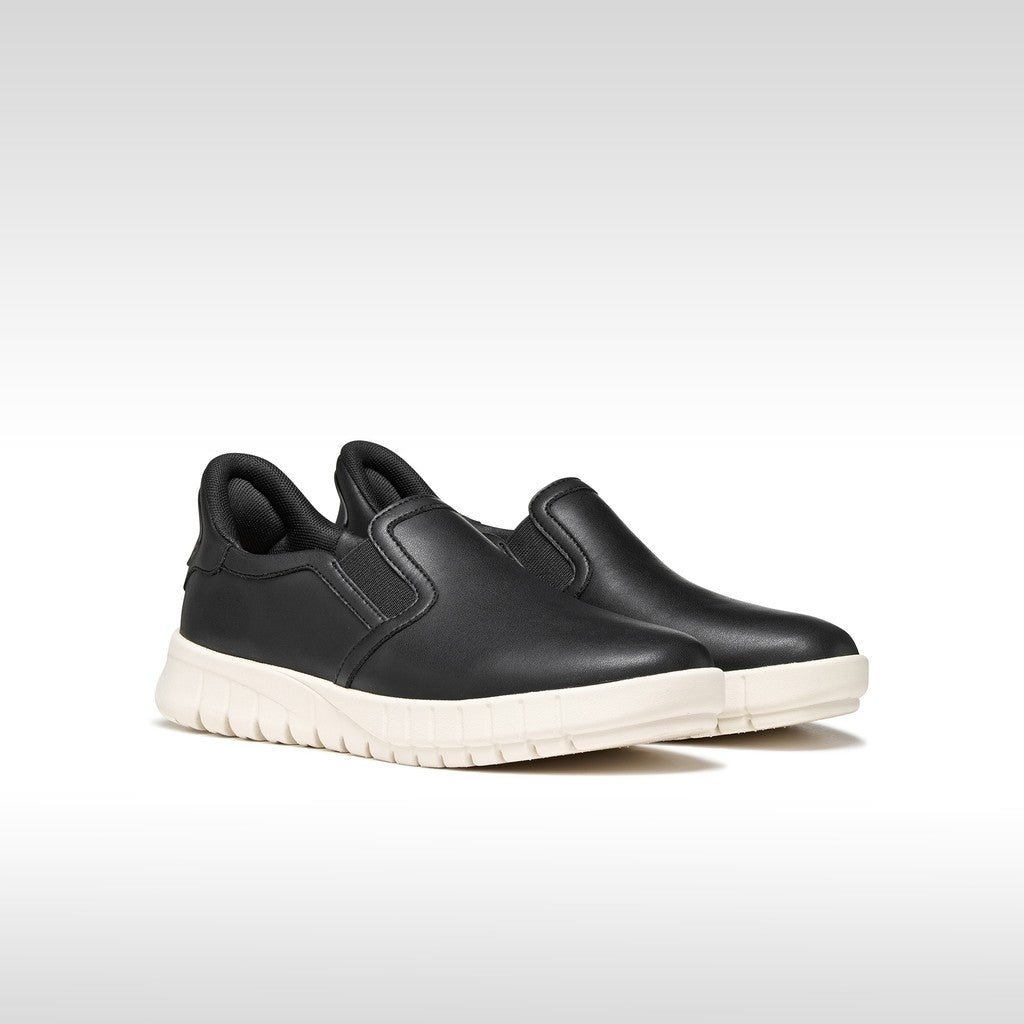 Black slip-on shoes with white soles on a light gray background