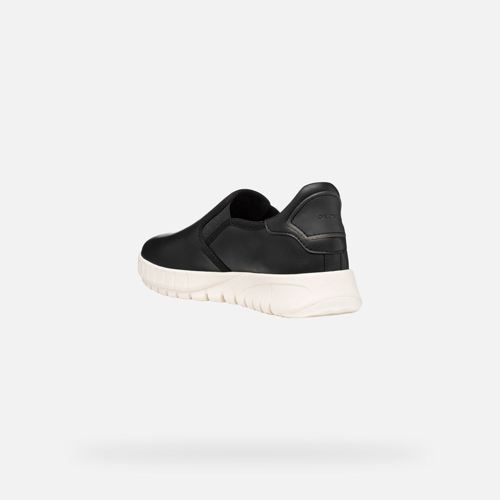 Black slip-on sneaker with white sole on a light gray background