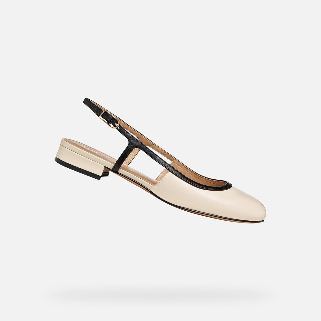 Beige flat shoe with black strap on a light gray background