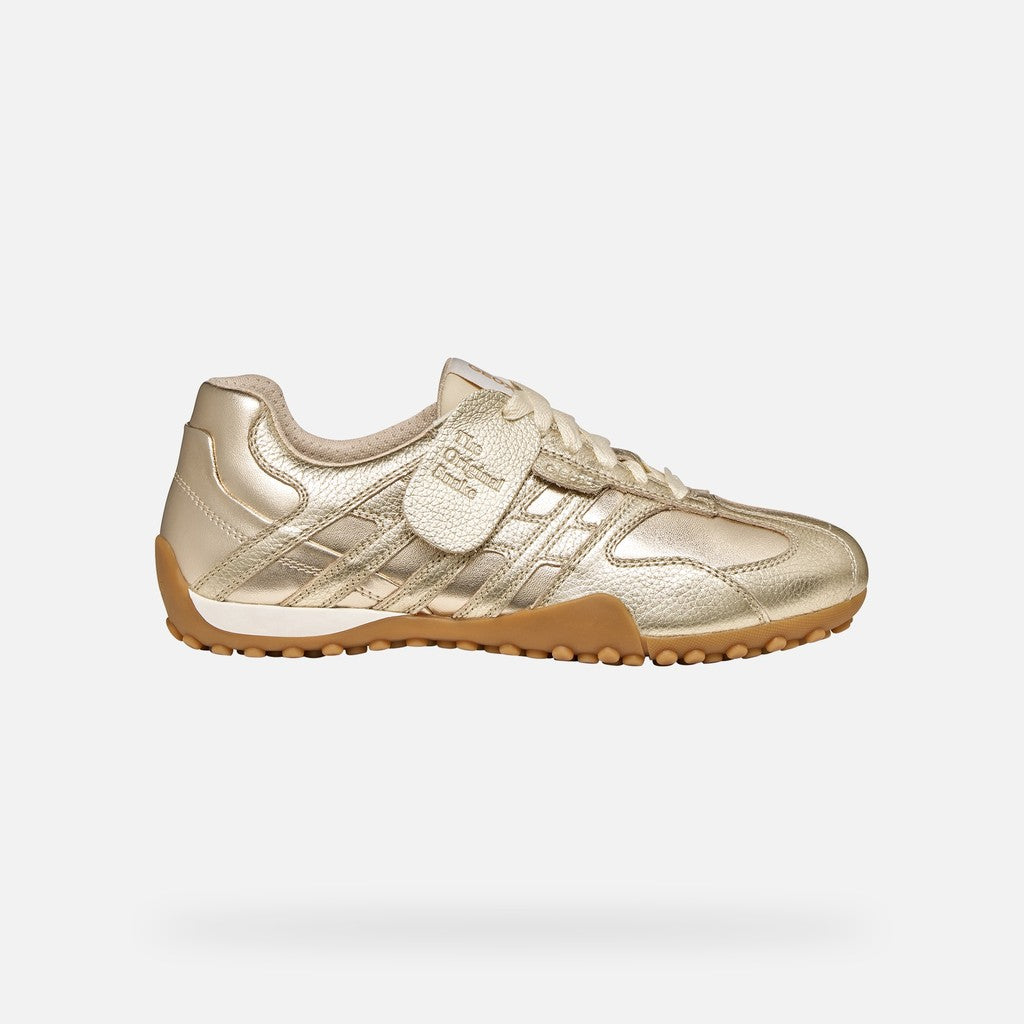Gold sneaker with brown sole on a white background