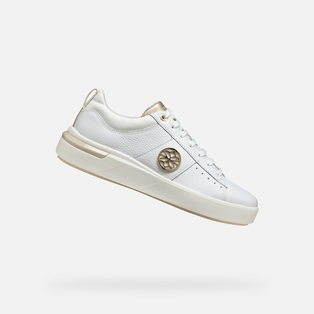 White sneaker with a gold logo on a light gray background