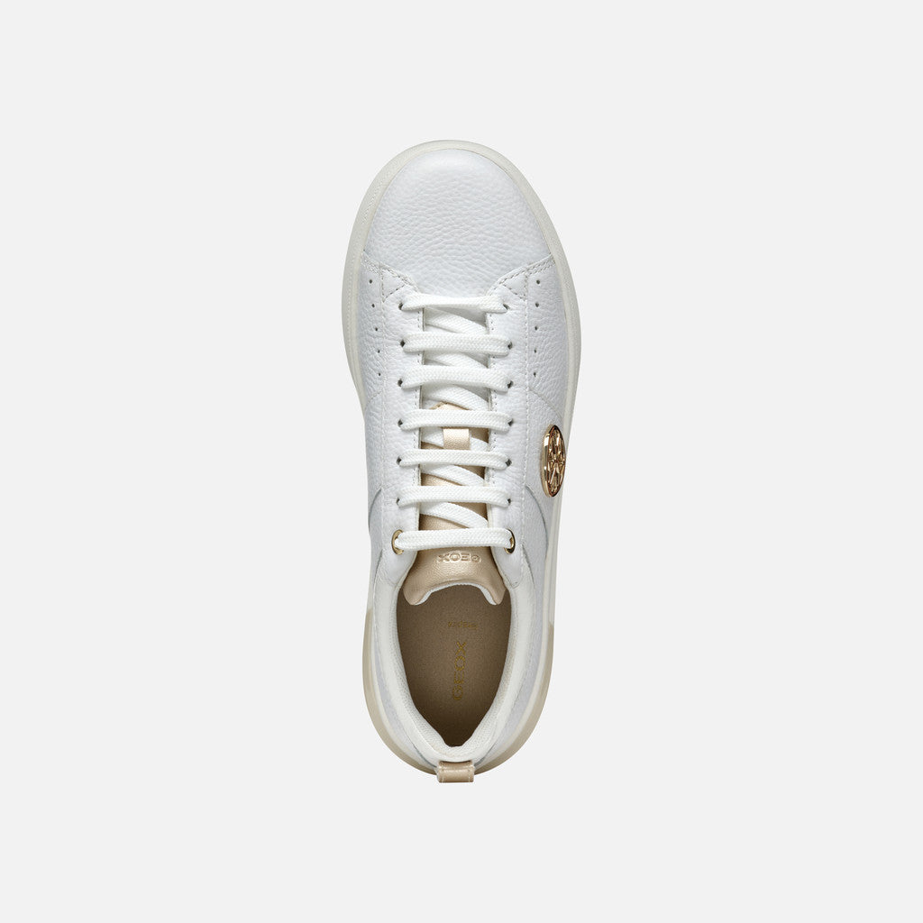 White sneaker with a gold logo on a light gray background