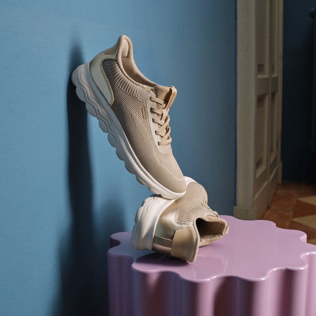 Beige sneaker on a purple stand against a blue wall