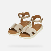 Pair of beige sandals with brown soles on a white background
