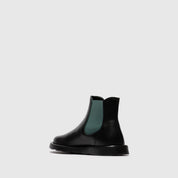 Black Chelsea boot with green lining on a light gray background