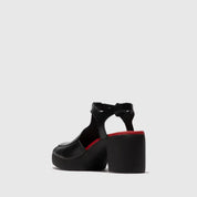 Black platform sandal with red sole on a white background