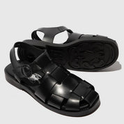Black sandals with woven straps on a light gray background