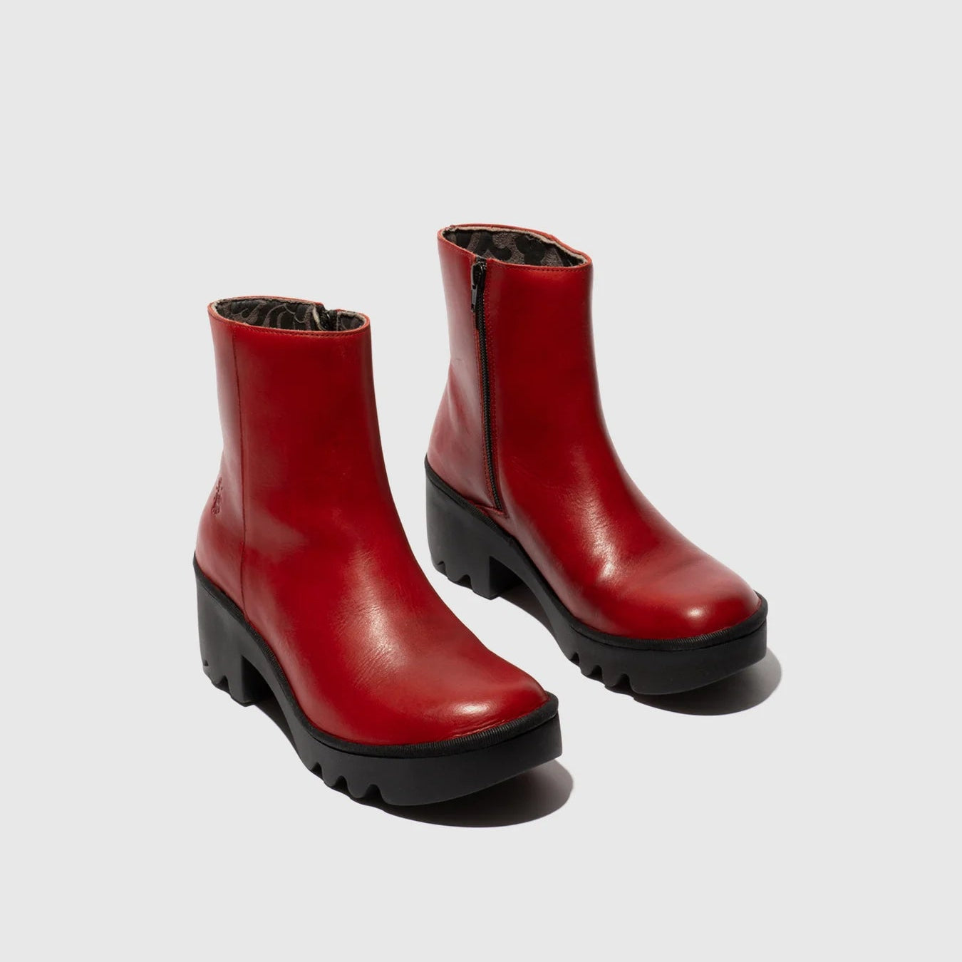 Pair of red ankle boots on a light gray background