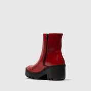 Red ankle boot with a black sole on a white background