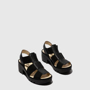 Black sandals with gold accents on a light gray background