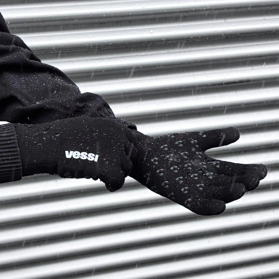 Black gloves with 'vessi' branding on a metallic surface