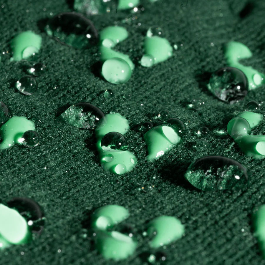 Close-up of green water droplets on a textured surface