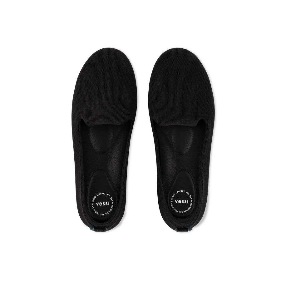 Pair of black slippers with 'Vessi' branding on a white background