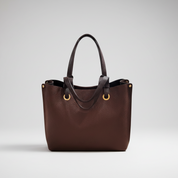 Brown leather handbag with gold accents on a white background