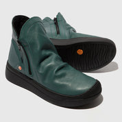 Green leather shoes with black soles on a light gray background