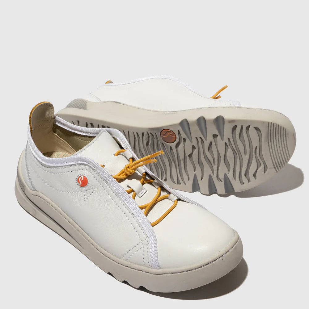 White sneakers with yellow laces on a light gray background