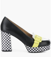 A black leather platform pump with a checkerboard patterned block heel and platform, featuring a white toe cap, a bright yellow strap detail, and a matching yellow buckle.
