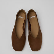 A pair of brown suede flat shoes with square toes, shown from a top-down view on a light gray background. The brand name 'CAMPER' is printed in white on the insole of each shoe.