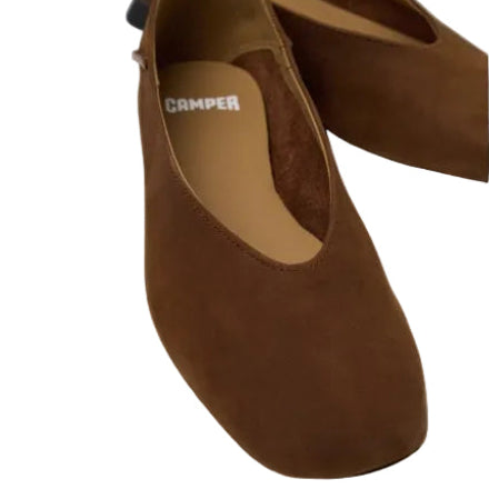 A pair of brown suede flat shoes with a low block heel, featuring a tan insole with the brand name 'CAMPER' printed in white. The shoes are photographed on a clean, light gray background.
