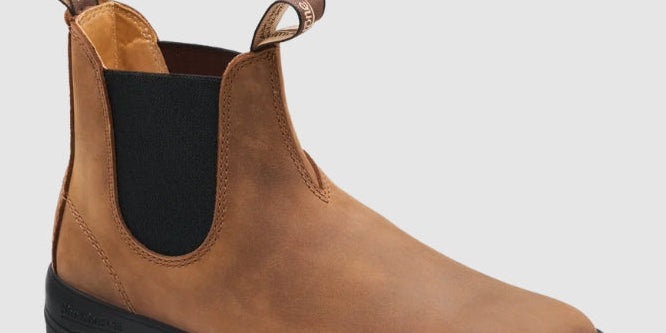 A single brown leather Chelsea boot with a black elastic side panel and a black rubber sole, shown from a three-quarters angle on a light gray background.